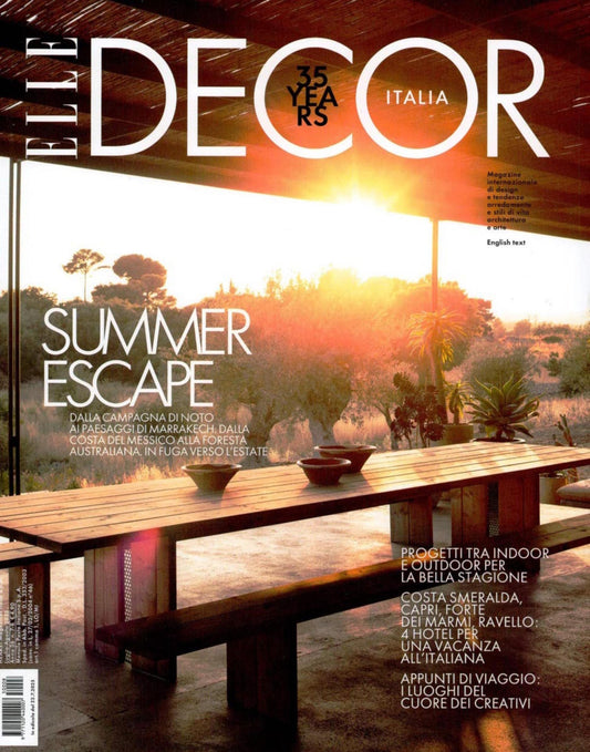 Front cover of ELITE DECOR ITALIA magazine featuring a modern interior scene with a glass table, black chairs, a warm yellow pendant light, and the headline 'SENSORY DESIGN'.