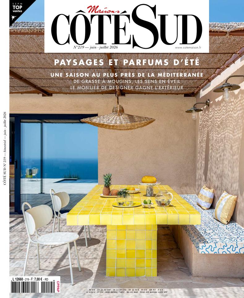 Cover of Maison du Coté Sud magazine, issue number 219 from June 2026, featuring a bright Mediterranean outdoor dining scene with a yellow tiled table, white chairs, patterned cushions, and a blue sea view in the background.