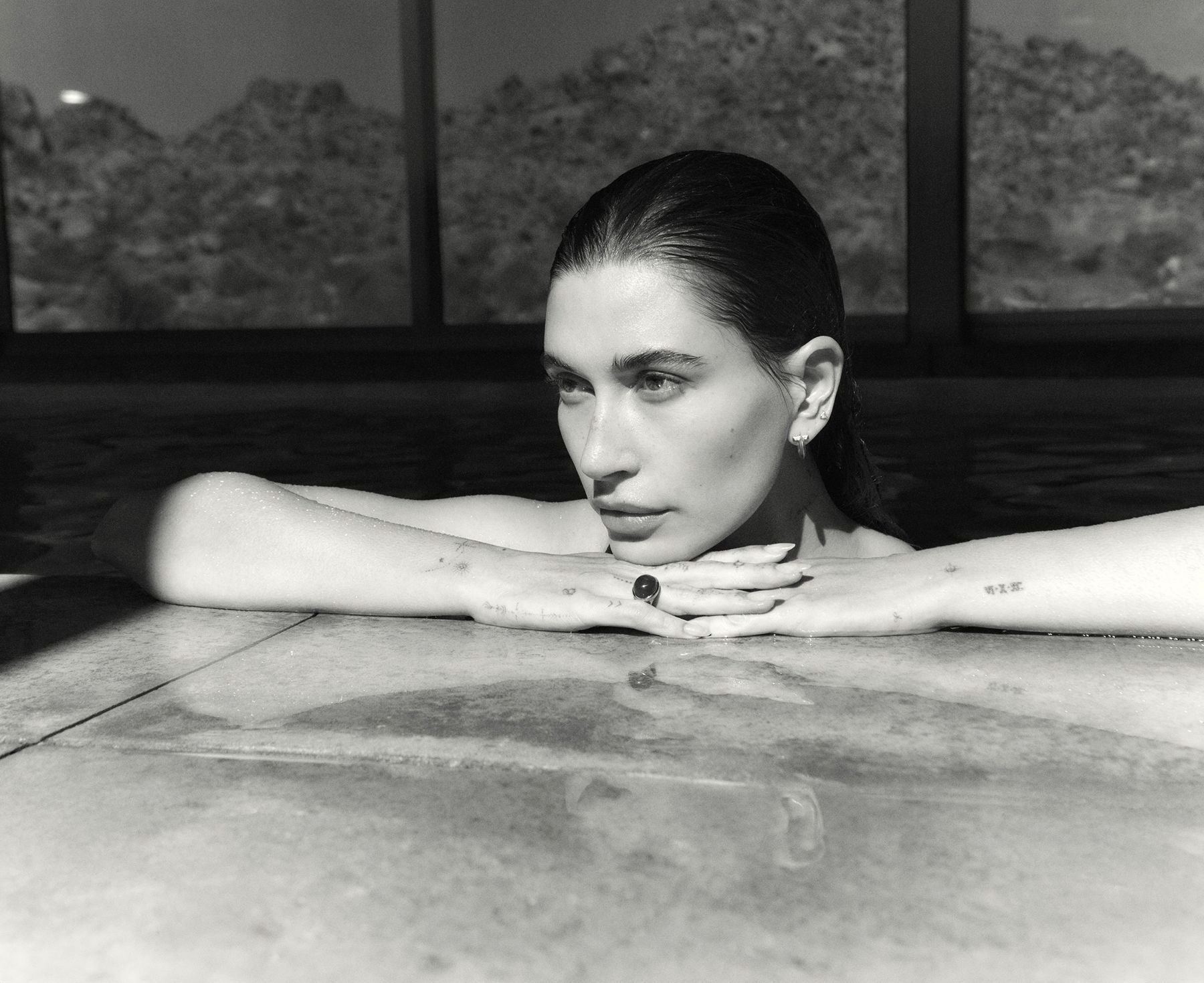 Hailey Bieber sitting in a hot tub with a scenic background