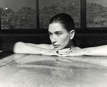 Hailey Bieber sitting in a hot tub with a scenic background