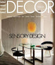 Front cover of ELITE DECOR ITALIA magazine featuring a modern interior scene with a glass table, black chairs, a warm yellow pendant light, and the headline 'SENSORY DESIGN'.