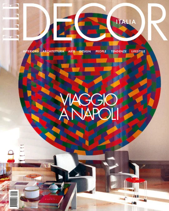 The Decor Italia magazine cover featuring a large colorful circular pattern on the wall above a modern living room interior with chairs and a coffee table. The headline reads 'Viaggio Napoli'.