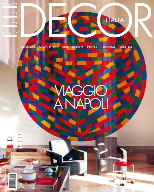 The Decor Italia magazine cover featuring a large colorful circular pattern on the wall above a modern living room interior with chairs and a coffee table. The headline reads 'Viaggio Napoli'.